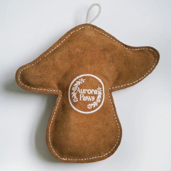 A brown suede mushroom-shaped ornament with white stitching and a circular white embroidered logo reading 'Aurora Pensa' in the center, shown against a plain white background.