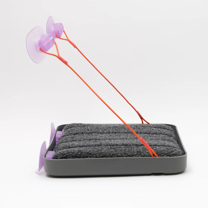 Gray pet mat with purple suction cups and orange string on a white background