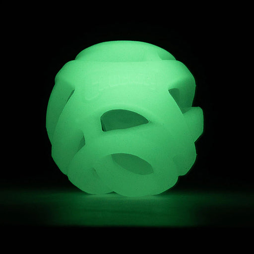 A glowing green interlocking ball-shaped toy or dog toy, photographed against a solid black background.