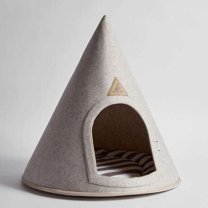 A cone-shaped felt pet house in light gray with a triangular wooden brand plaque on the front and a striped cushion inside, photographed on a clean light gray background.