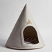 A cone-shaped felt pet house in light gray with a triangular wooden brand plaque on the front and a striped cushion inside, photographed on a clean light gray background.