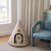 a small dog inside a cone-shaped pet bed by a window.
