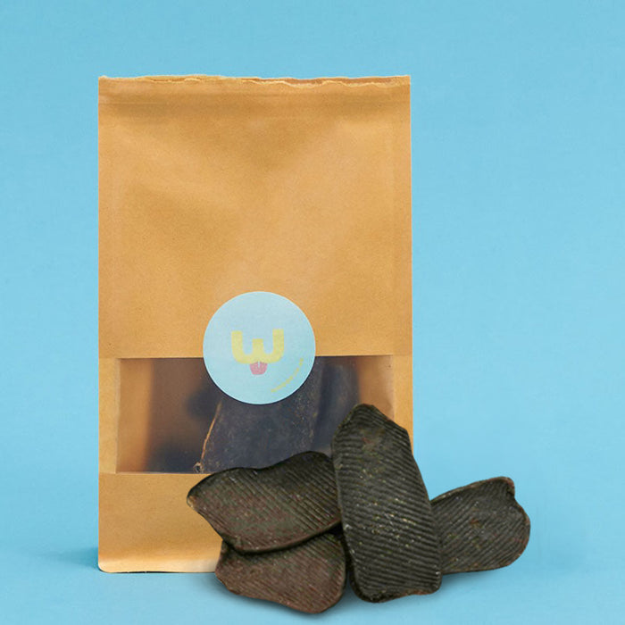 Kraft paper bag with a blue label containing dark-colored items on a blue background
