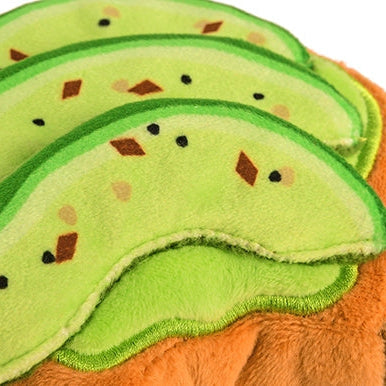 Avocado-shaped dog toy with brown seeds on a white background