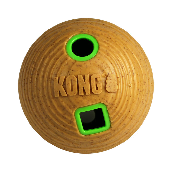 A Kong brand dog toy ball in a textured tan material, featuring a circular hole with a bright green rim and a square slot with a matching green border, on a plain white background.