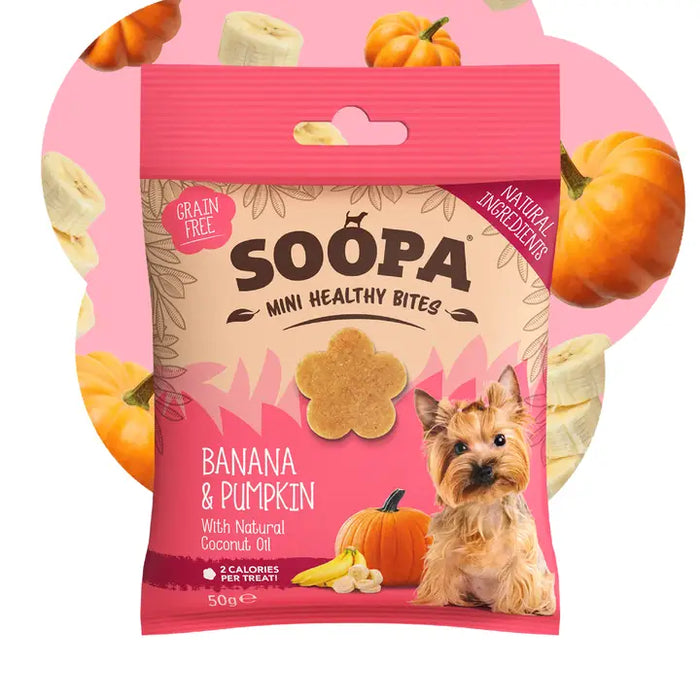 A package of Soopa Mini Healthy Bites dog treats in Banana & Pumpkin flavor, featuring a pink and beige bag with an illustration of a small dog, a banana piece, and pumpkins. The background is a soft pink with decorative pumpkin and banana graphics.