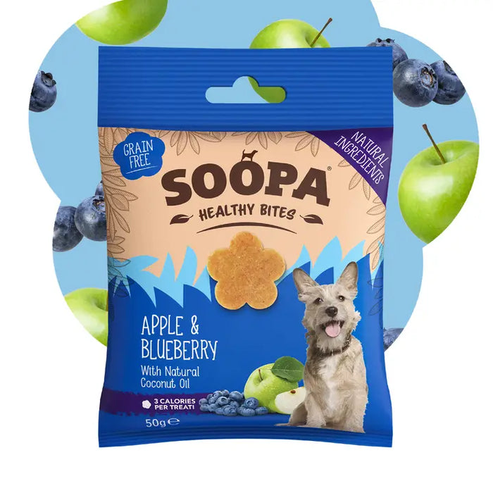A 50g bag of Soopa Healthy Bites dog treats in Apple & Blueberry flavor. The packaging is blue and beige with an illustration of a small dog and a treat, set against a circular graphic background of green apples and blueberries on a light blue field.