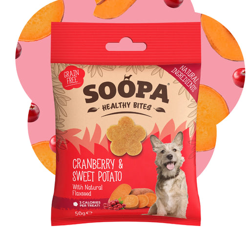 A package of Soopa Healthy Bites Cranberry & Sweet Potato dog treats, featuring a red and beige bag with a picture of a dog and illustrations of treats, set against a pink background with orange and red circular accents.
