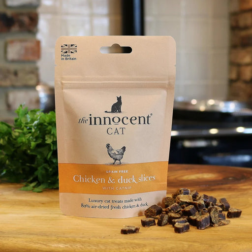 Package of 'the innocent CAT' chicken and duck slices on a wooden surface with treats visible.