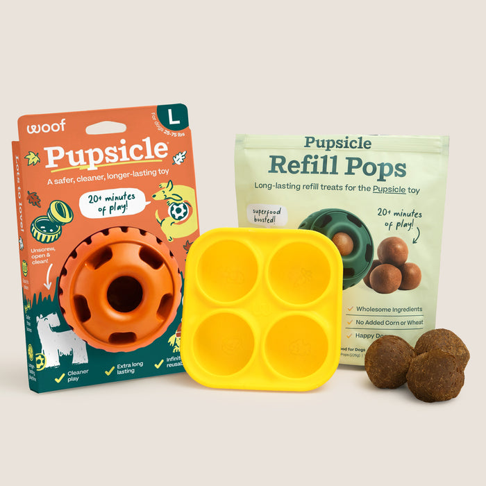 A dog toy set on a light beige background, including a Uroof Pupsicle toy box, a yellow three-compartment silicone mold, a pouch of Pupsicle Refill Pops, and three brown treat balls.