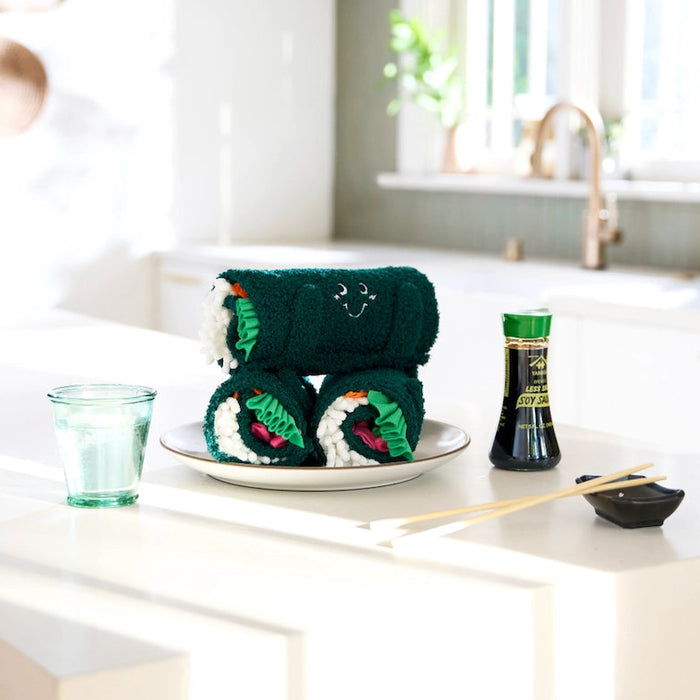 Modern kitchen with a table set for sushi, featuring a bottle of wasabi and a glass of water.