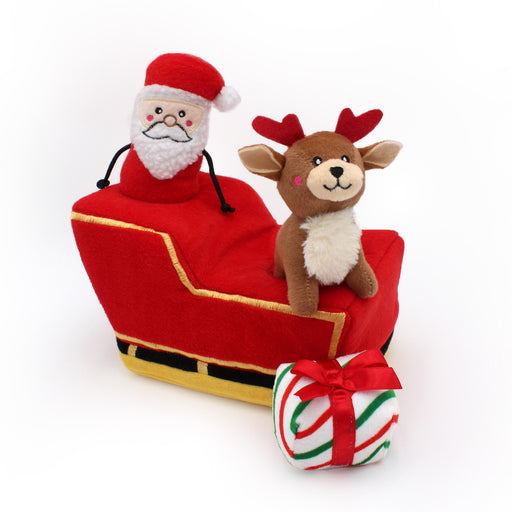 Plush Santa Claus and reindeer in a red sleigh with a candy cane gift on a white background