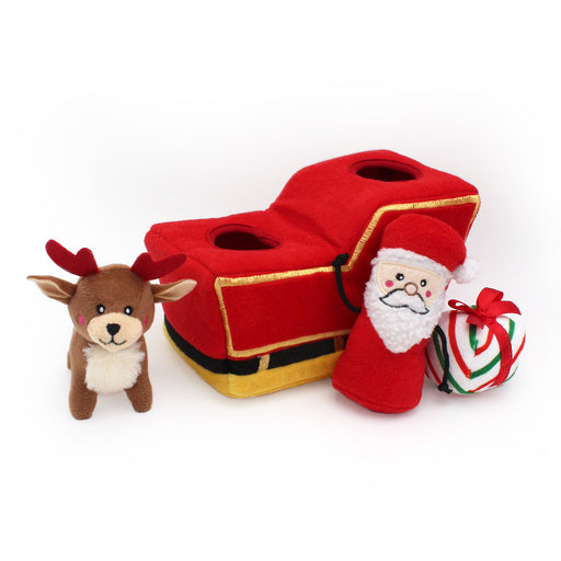 Red toy sleigh with Santa Claus figure, reindeer, and candy cane on a white background