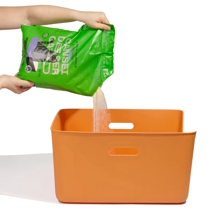 Green bag of dog food being poured into an orange storage bin on a white background