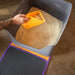 Person using a yellow scoop to clean a cat litter box with brown litter.