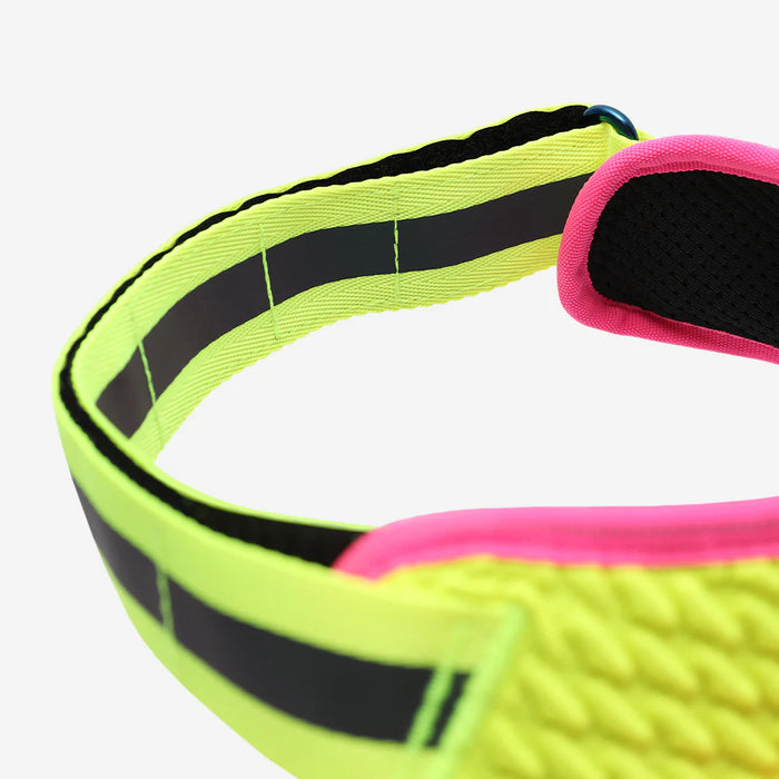 Neon green and pink harness with reflective stripes on a white background