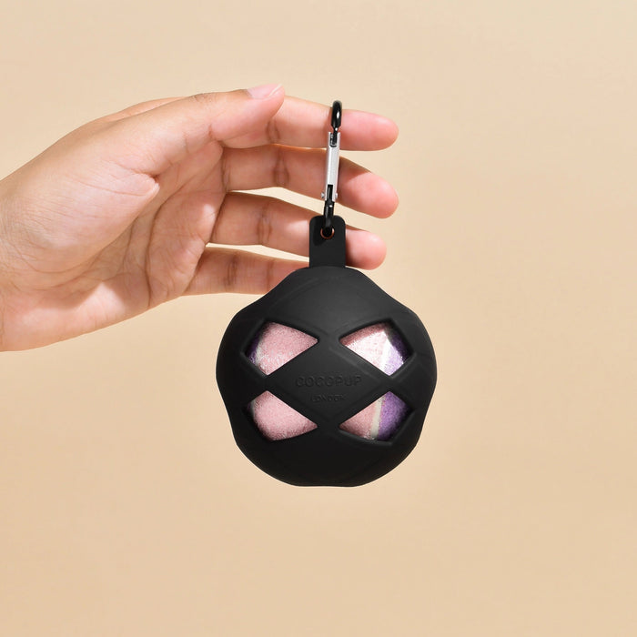 Hand holding a black pet toy with a beige background