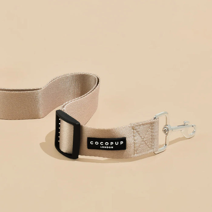 Beige dog leash with black clip and COCOPUP London label on a beige background