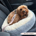 Dog sitting in a car seat cover with a visible brand logo.