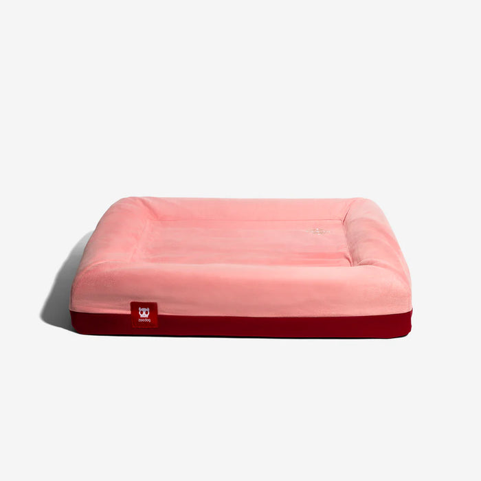 Pink pet bed with a red base on a white background