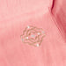 Close-up of a pink fabric with an embroidered design.