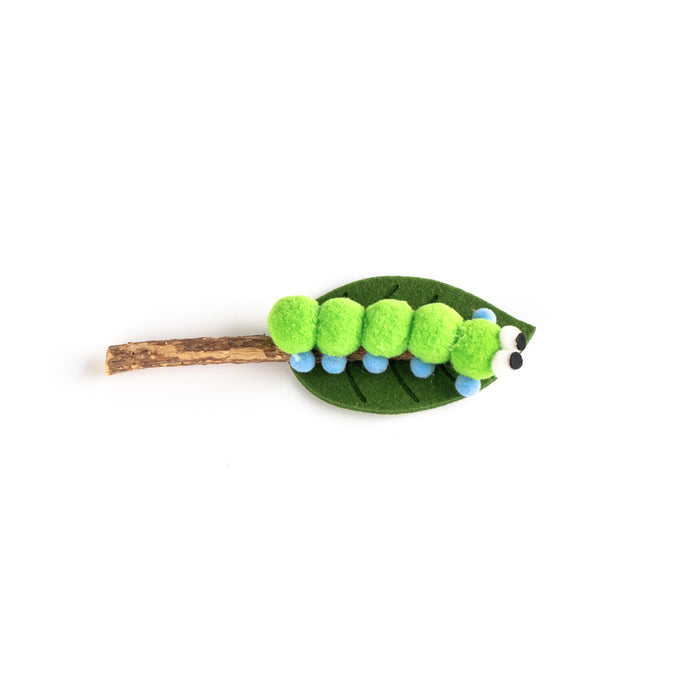 A cute caterpillar hair clip made from felt, featuring bright green segmented body segments, a dark green leaf base, a brown twig-style back, and small blue accents.