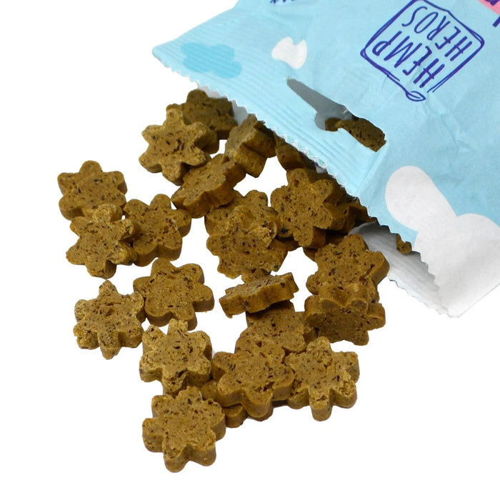 Brown flower-shaped dog treats spilling out of a light blue and white bag labeled 'HEMP HERO'S' on a white background.