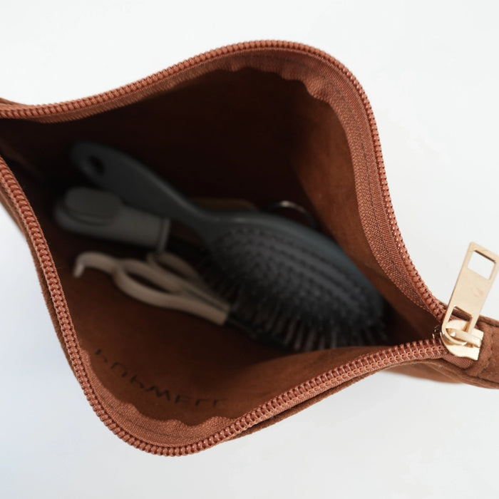 A brown zippered cosmetic pouch shown open, revealing a dark gray hairbrush and a white hair tie inside. The pouch has a gold-tone zipper pull and the brand name 'LOOMEE' printed inside.