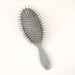 A gray oval hairbrush with black bristles, shown on a plain white background.