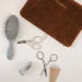 Pupwell grooming kit laid out on a white background, including a gray hairbrush, white nail clippers, silver nail scissors, a gray nail file, and a brown velvet pouch with gold PUPWELL branding.
