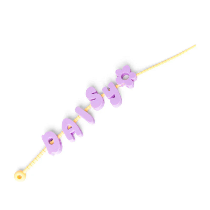 Purple letter beads spelling 'daisy' on a yellow string against a white background
