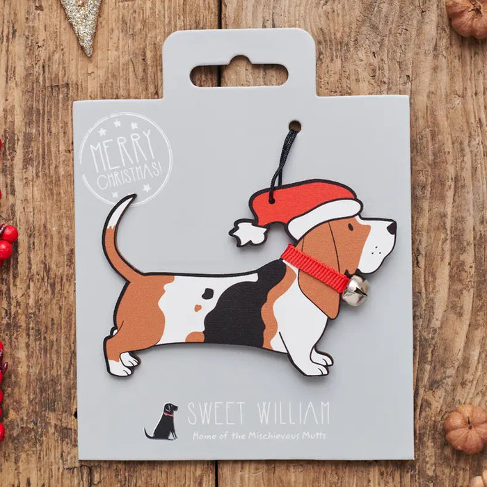 A personalized Christmas beagle ornament on its custom grey backing card, displayed on a rustic wooden surface with holiday decorations.