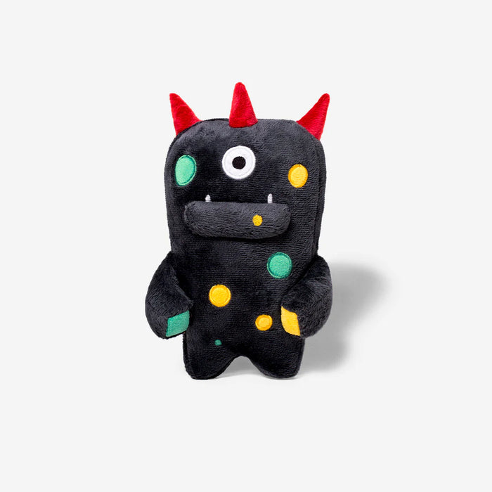 Black plush toy with colorful spots and red horns on a white background