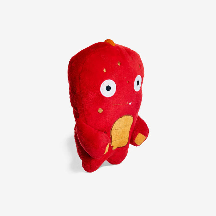 Red plush toy with white eyes and orange accents on a light gray background