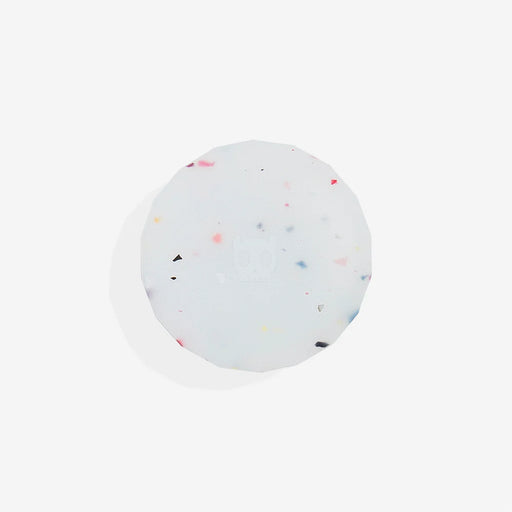 Round, white airtag holder with colourful specks on a light grey background