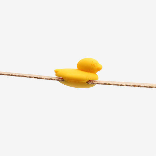 Yellow rubber duckling on a branch against a white background