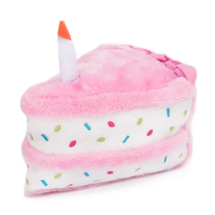 Plush toy shaped like a birthday cake with pink icing, white base, and colorful sprinkles on a white background.