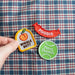 Scouts Honour "Wiggle But" iron-on badge with orange peach icon, grouped together with a variation of other patches