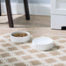 The Manor White Dog Bowl on a patterned grey and white carpet.