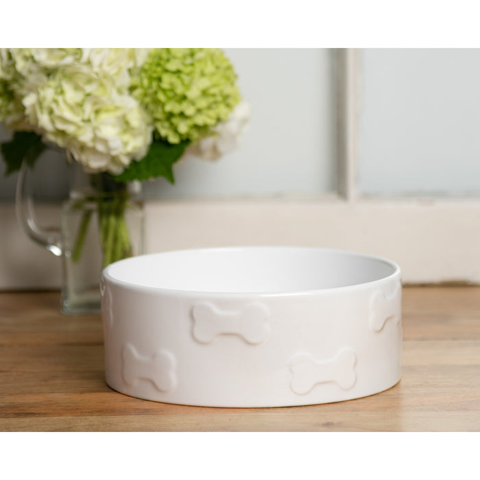 The Manor White Dog Bowl on a wooden floor. In the background some hydrangea's are placed.