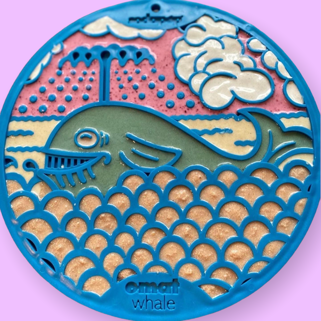 A blue silicone lick mat with a whale design, intended for use with dogs. filled with colourful soft treats