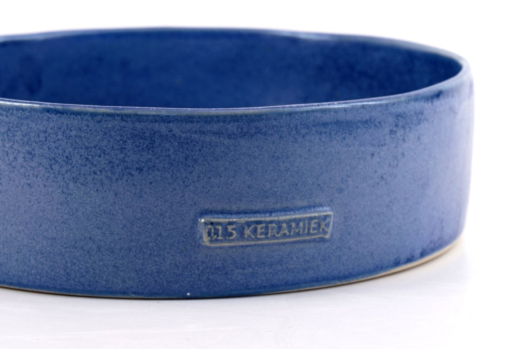 Blue ceramic hand made dog bowl by "015 Keramiek" placed on a white background, showing the "015 Keramiek" logo.