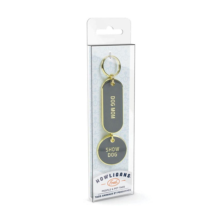 Howligans Keychain set in grey enamel and gold details. The set consists of a dog tag and keychains stating: "Dog Mom" and "Show Dog". The set is in its packaging and pictured on a white background.